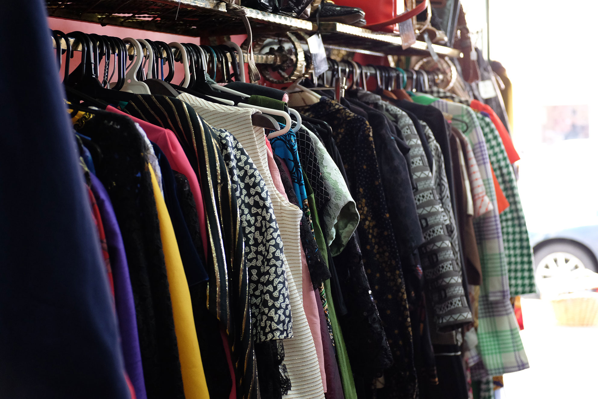 A rack of colorful secondhand clothing on hangers