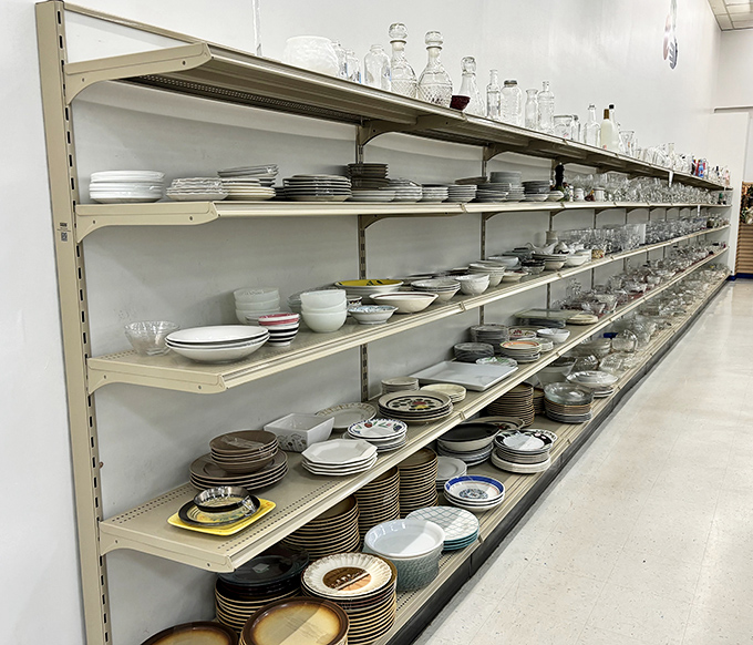 Long thrift-store shelves stacked with plates, bowls and glassware